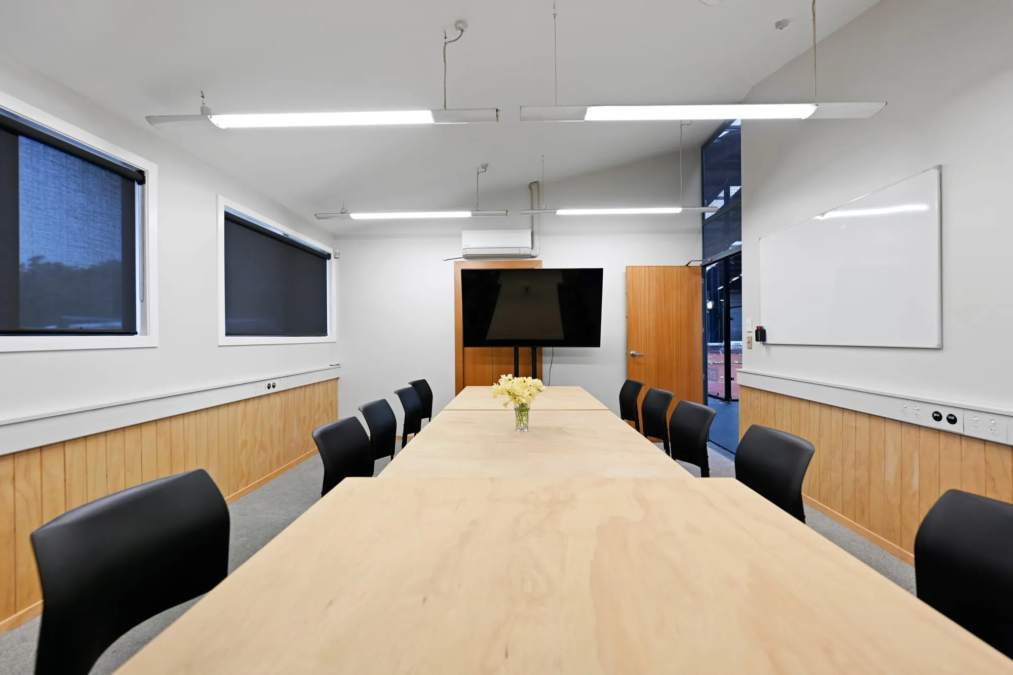 The meeting room set as a long boardroom table, with a wall screen at the far end