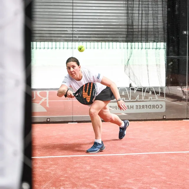 A player lunging for a low volley as the ball drops