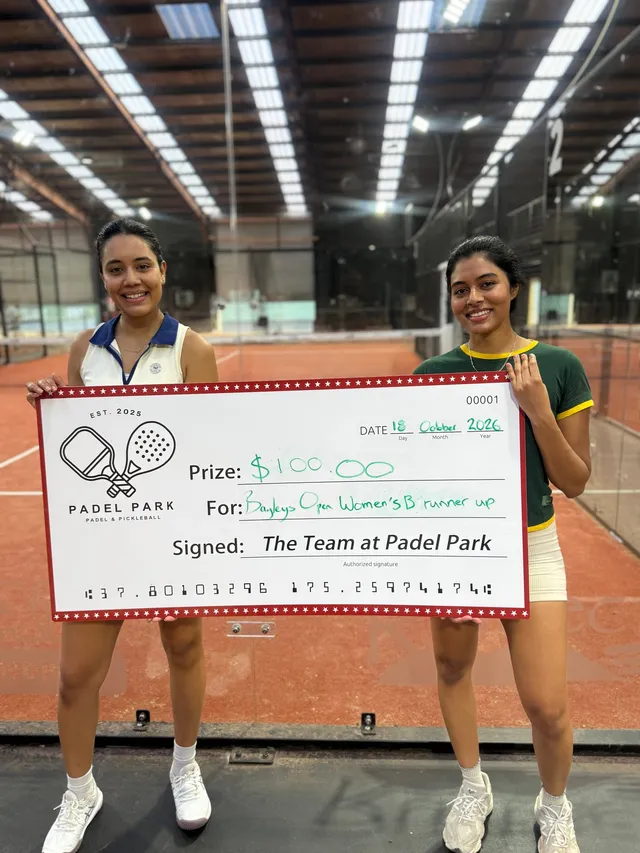 Two players on court holding a prize cheque