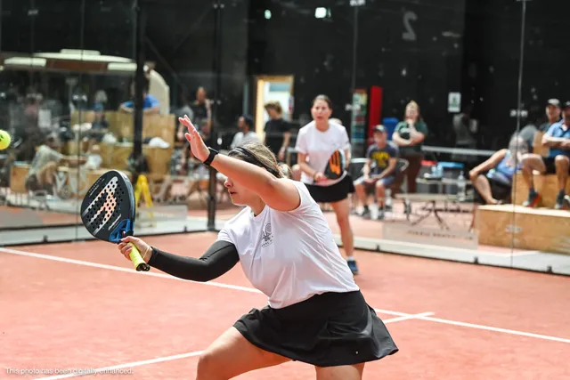 A player stretching wide for a low forehand with the crowd behind