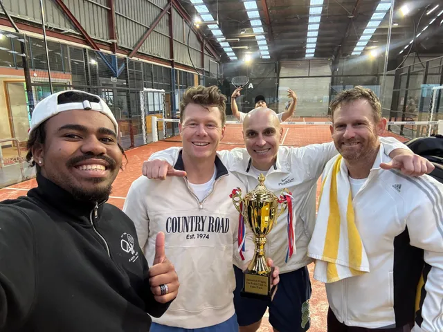 Four players celebrating with a trophy on court