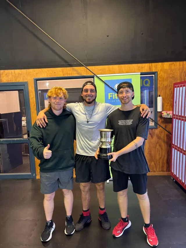Three players with a silver trophy, one giving a thumbs up