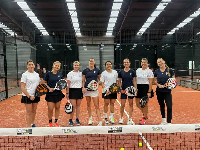 A women's team of eight lined up at the net with their rackets