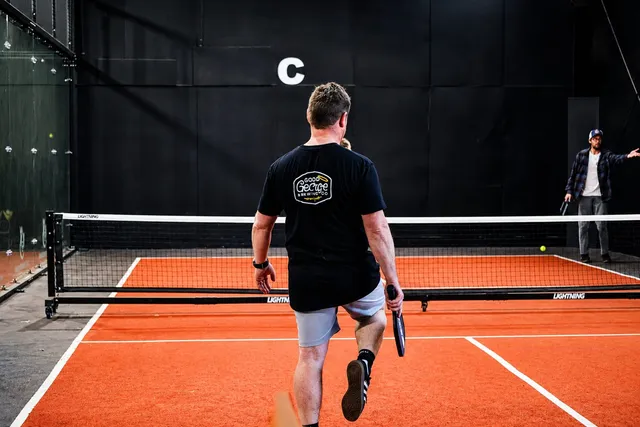 A player walking out onto a lit padel court