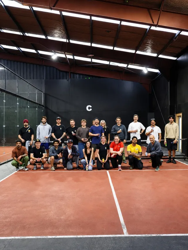 A big group gathered at the end of a court for a team photo