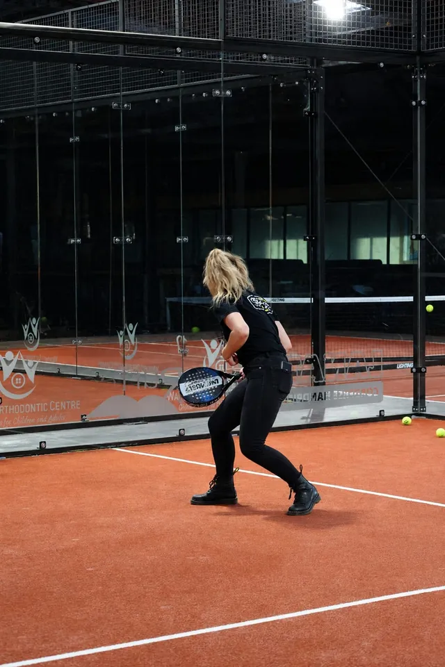 A player in black ready for the ball on a padel court