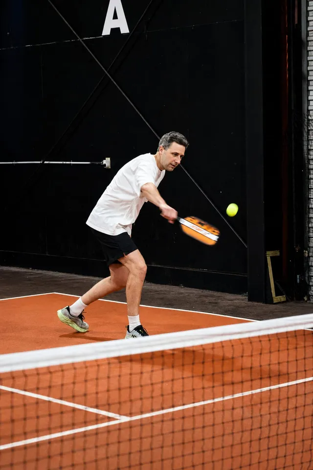 A player hitting a forehand near the back wall
