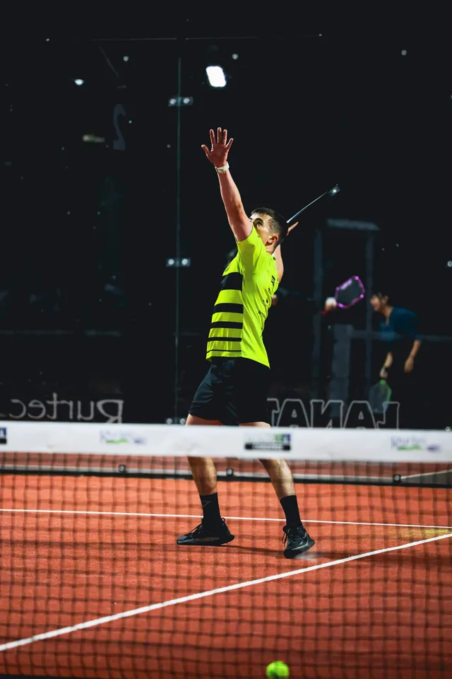A player stretching up for an overhead at the net