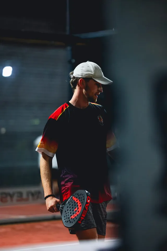 A player in a cap and red shirt waiting for the ball