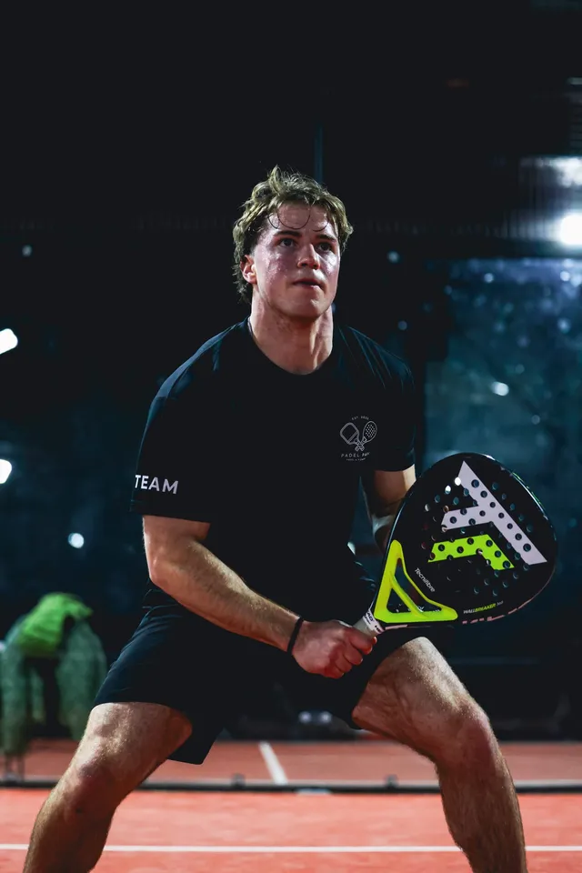 A player in the team tee crouched ready at the net