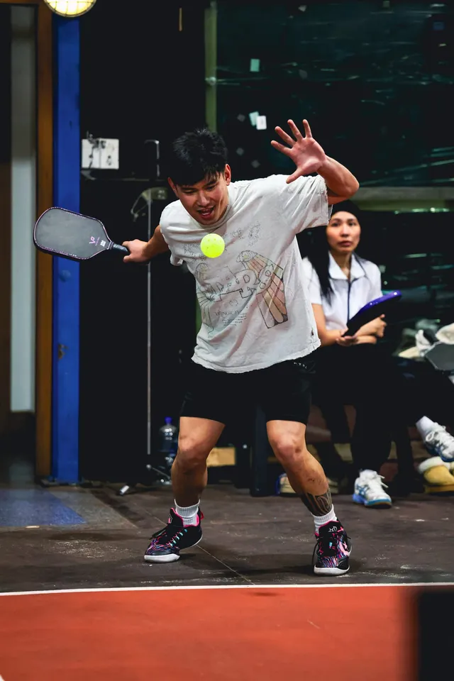 A pickleball player hitting a forehand with players waiting behind