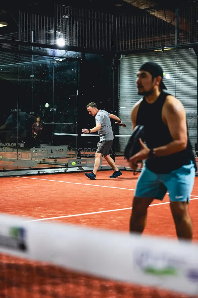 A player in a cap moving across a court at night