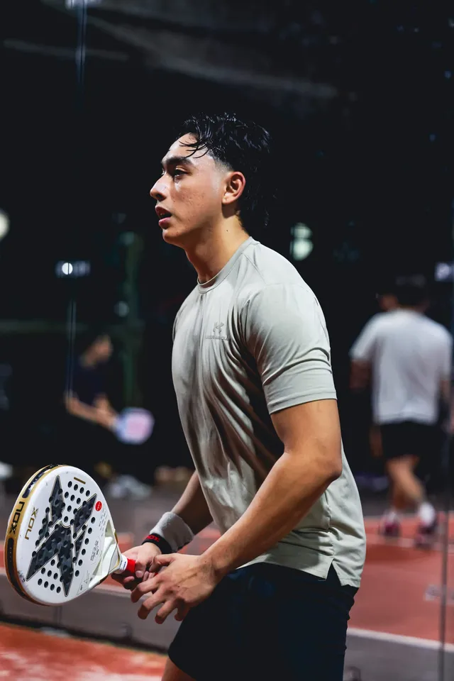 A player holding a padel racket, watching the ball