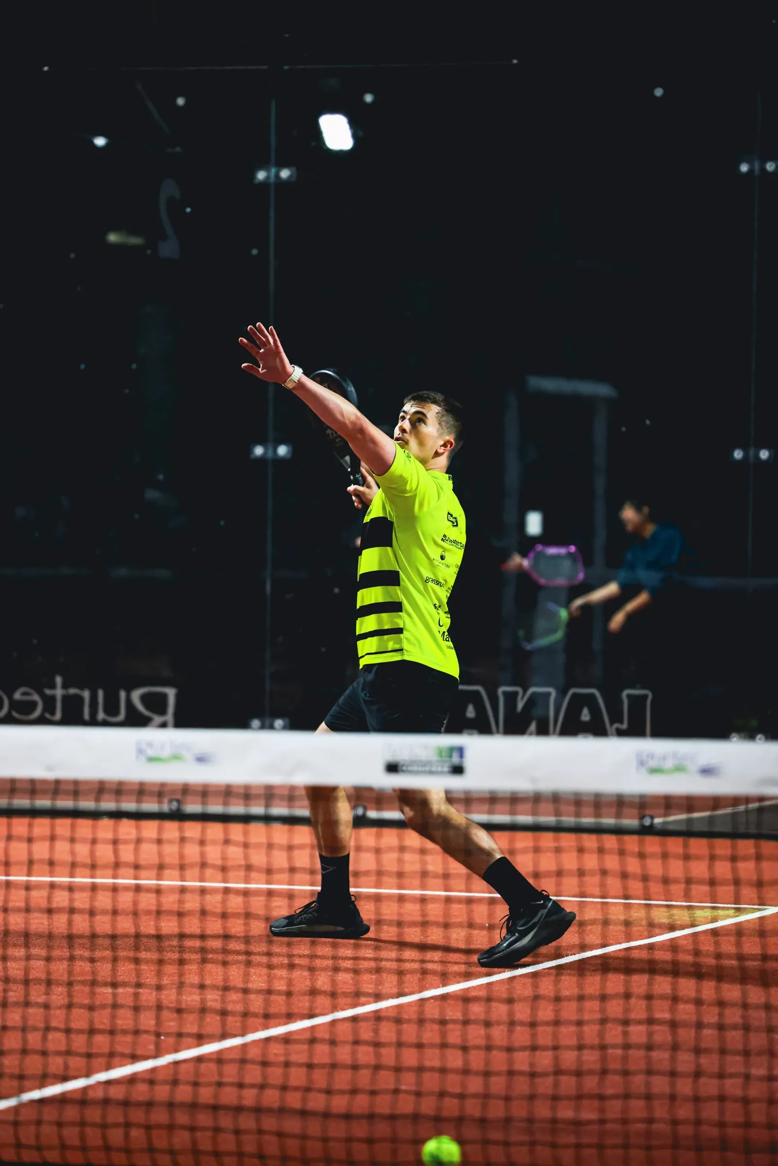 A padel player reaching up for an overhead