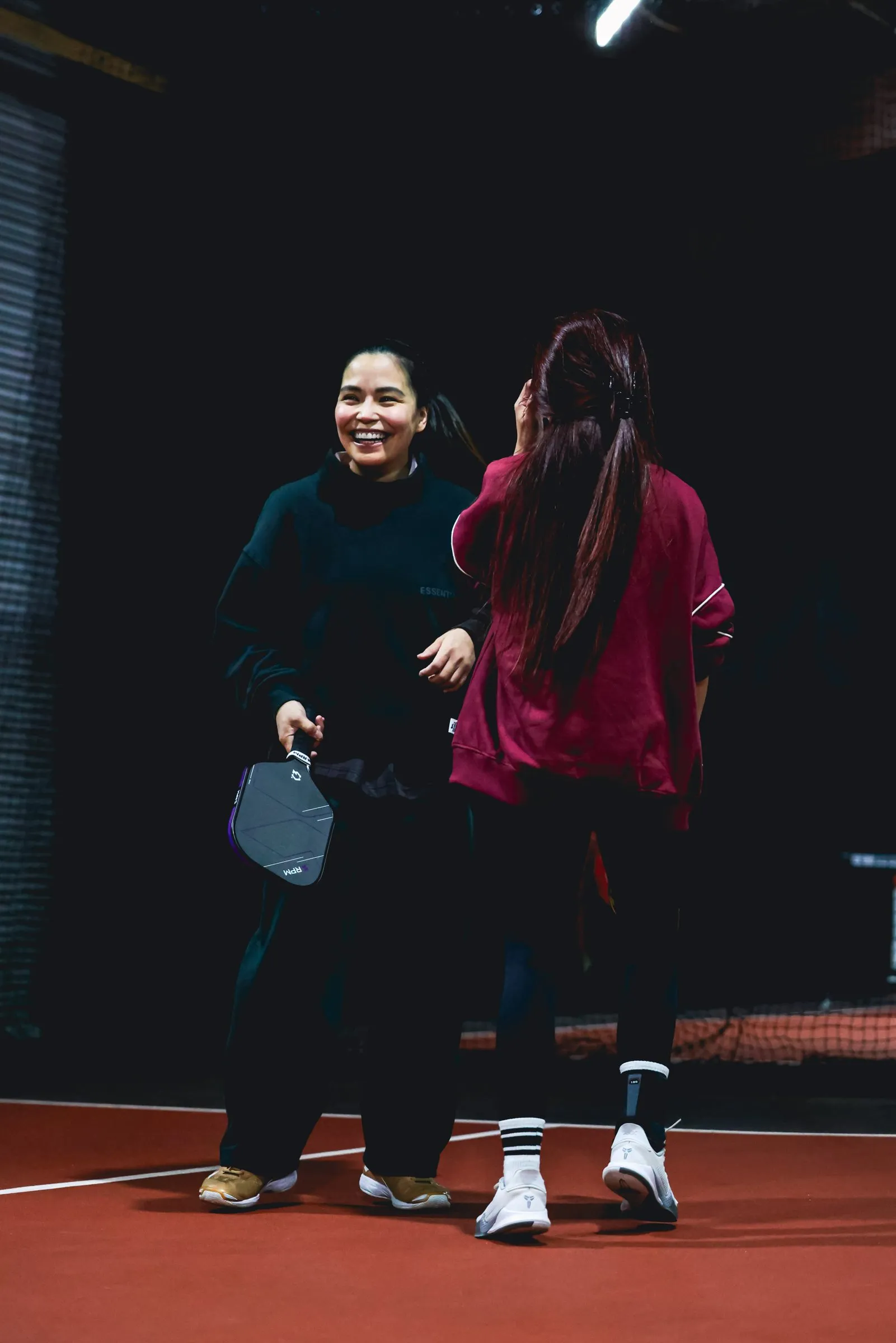 Two friends laughing between points on a pickleball court at the Park