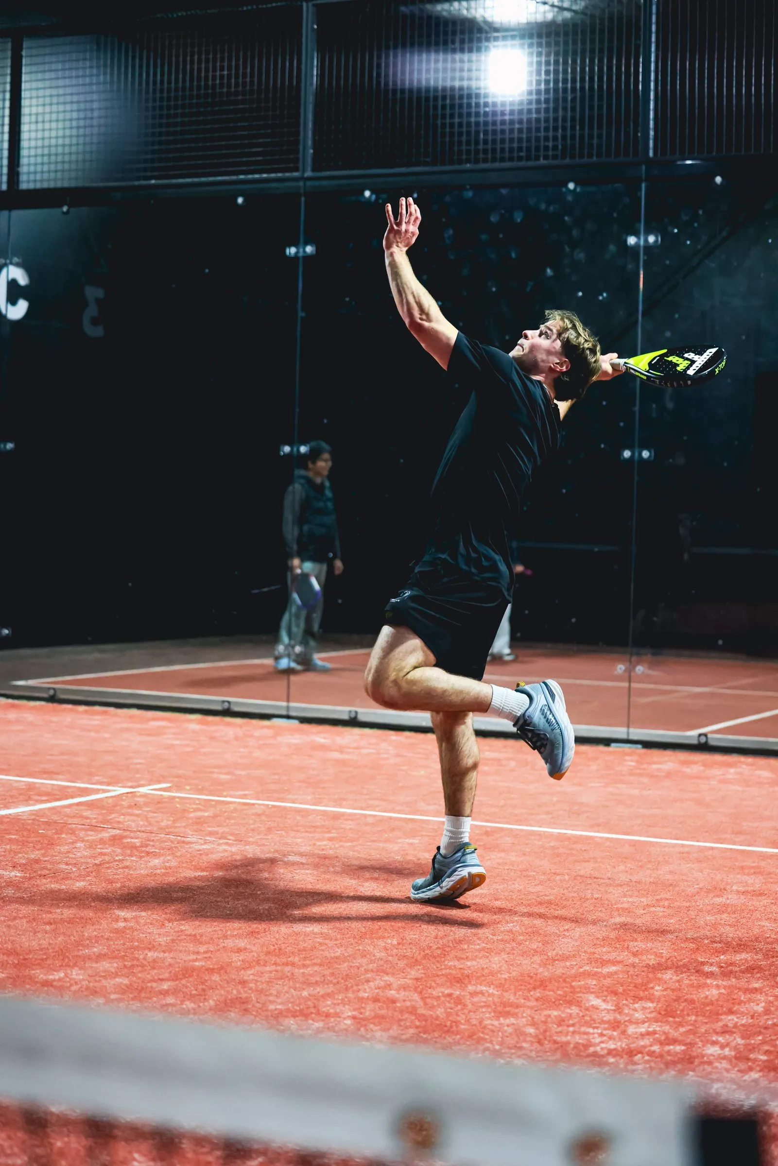 A padel player smashing on a full court