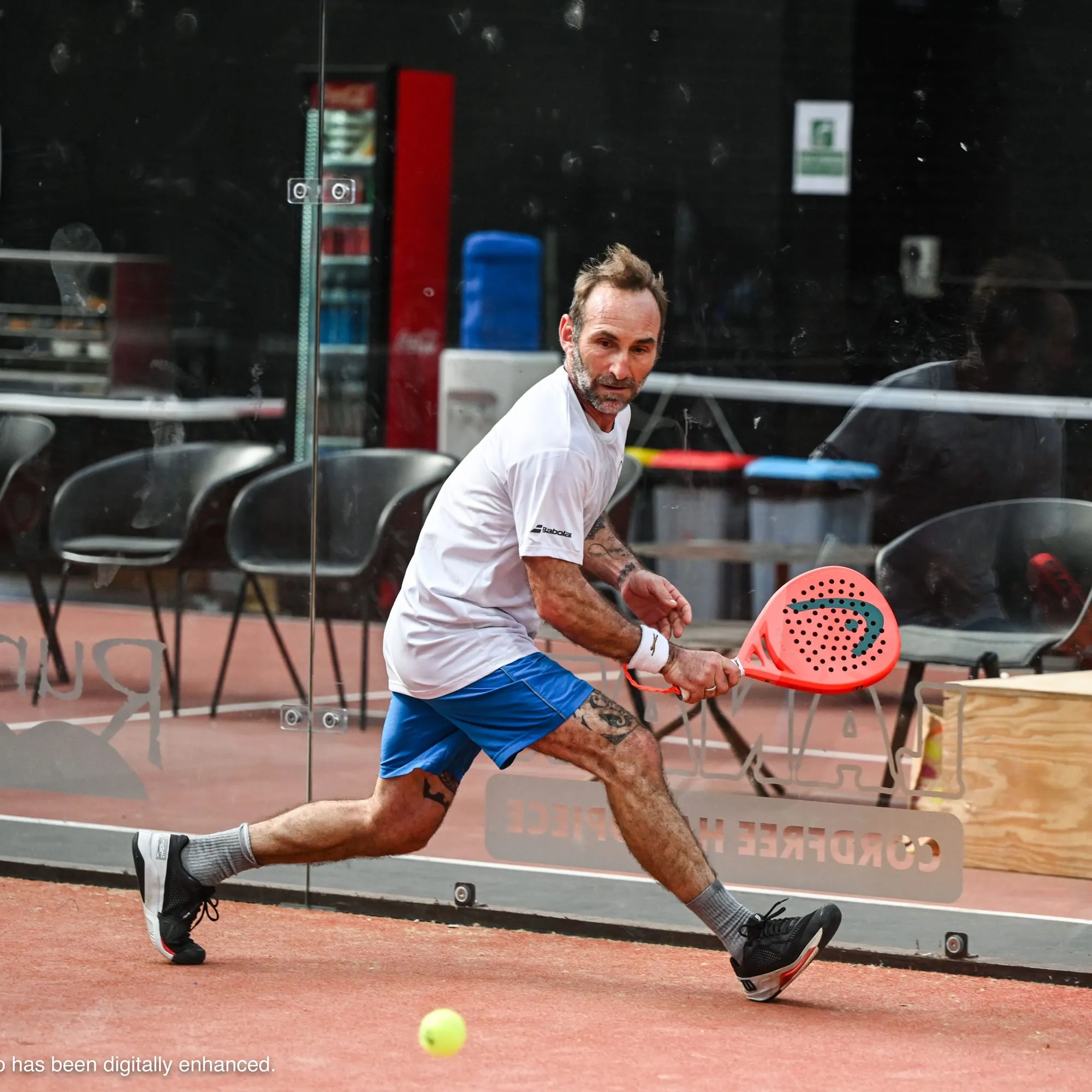 A padel player lunging into a low volley