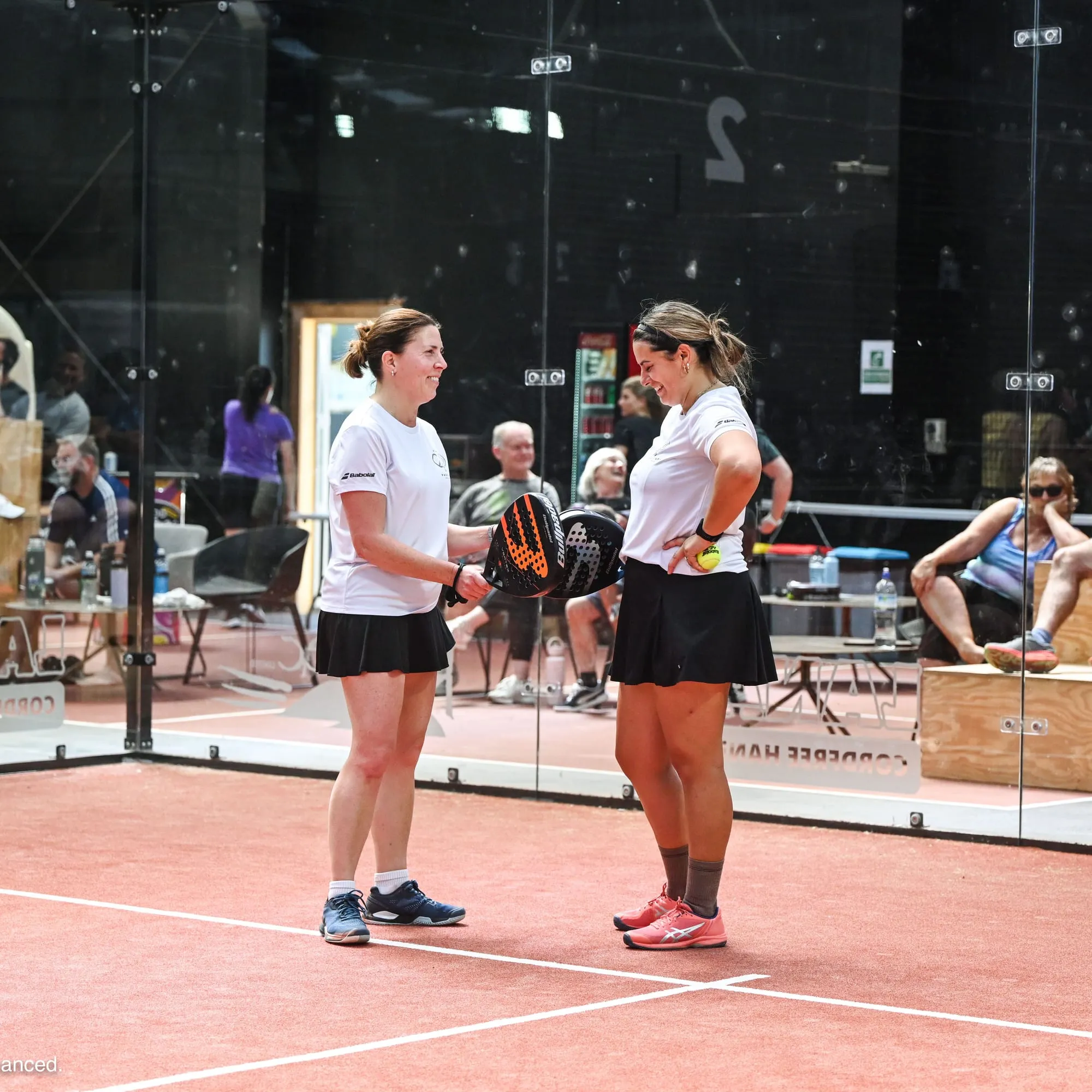 Two padel partners sharing a laugh between points