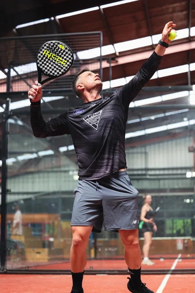 A player serving on a sunlit court